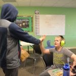two students giving each other a high five in the classroom
